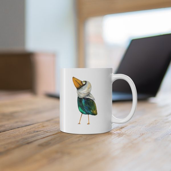 White ceramic coffee mug with a watercolor painting of a whimsical crow called Squawk mug is on a wooden table