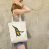 girl with a white canvas tote bag featuring a watercolor painting of a whimsical crow