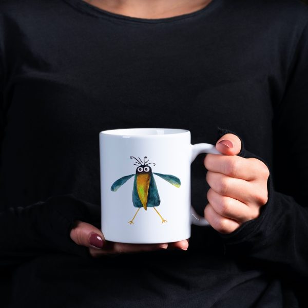 Woman in black blouse holding a white ceramic 11 oz coffee mug with a whimsical watercolor illustration of a crow