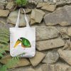 a white canvas tote bag featuring a watercolor painting of a whimsical crow hanging on a wall