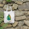 a white canvas tote bag featuring a watercolor painting of a whimsical crow bag is hanging on a wall