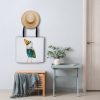 White Tote Bag hanging on a wall featuring a watercolor painting of a whimsical crow called Squawk