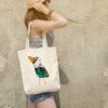 girl with a white canvas tote bag featuring a watercolor painting of a whimsical crow