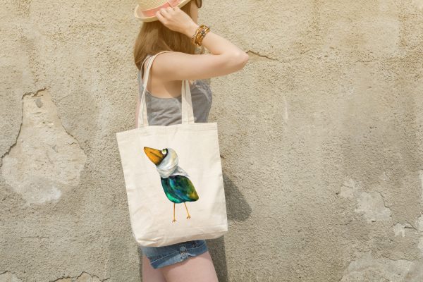 girl with a white canvas tote bag featuring a watercolor painting of a whimsical crow