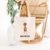 white canvas tote bag with a watercolor painting of a whimsical ant bag is on a bamboo chair
