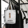 white canvas tote bag with a watercolor painting of a whimsical ant bag is hanging on a rack
