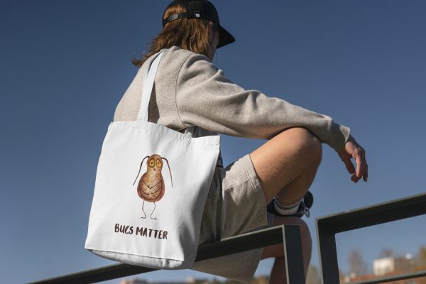 boy with a white canvas tote bag with a watercolor painting of a whimsical cockroach