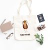 white canvas tote bag with a watercolor painting of a whimsical cockroach bag is on the floor
