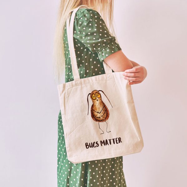 girl with a white canvas tote bag with a watercolor painting of a whimsical cockroach