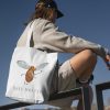 boy with a white canvas tote bag with a watercolor painting of a whimsical mosquito