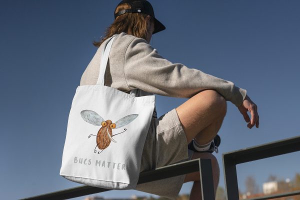 boy with a white canvas tote bag with a watercolor painting of a whimsical mosquito