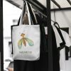white canvas tote bag with a watercolor painting of a whimsical green lacewing bag is hanging on a rack