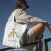 boy with a white canvas tote bag with a watercolor painting of a whimsical green lacewing