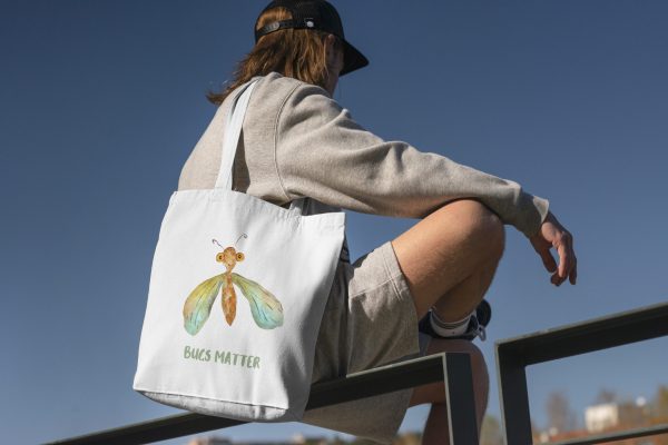boy with a white canvas tote bag with a watercolor painting of a whimsical green lacewing